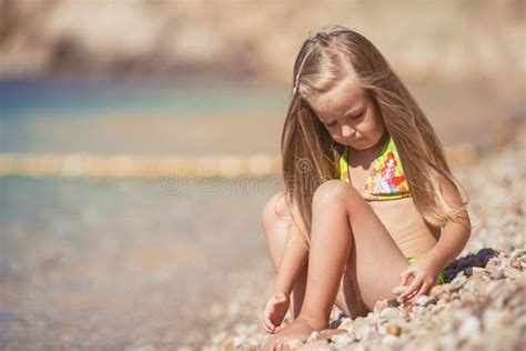 Kleines Mädchen Das Auf Dem Strand Nahe Dem Meer Sitzt Stockfoto