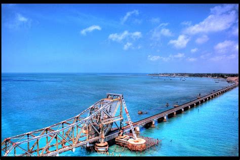 An Aerial View Of A Bridge Spanning The Ocean With Blue Skies And