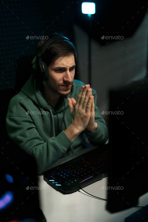 Stressed Male Cybersport Gamer Playing Video Game And Praying With Hope