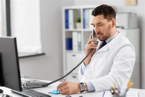 Male Doctor Calling On Desk Phone At Hospital Stock Image Image Of