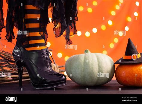 Witch Legs In Striped Stockings And High Heel Shoes With Pumpkins On An Orange Background Bokeh