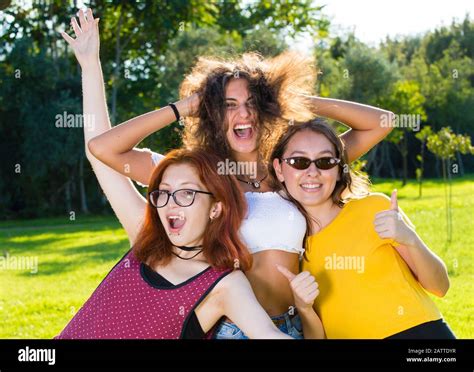 Three Girls Posing For Portrait For Fun Spreading Arms Showing Thumbs
