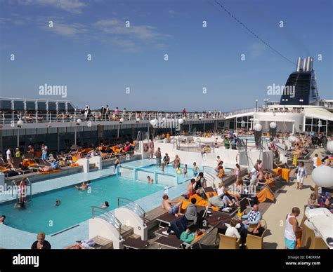 The Top Deck Of A Busy Cruise Ship With People Sitting Around The Stock