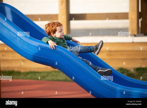 Boy Playing On Slide In Playground Stock Photo Alamy