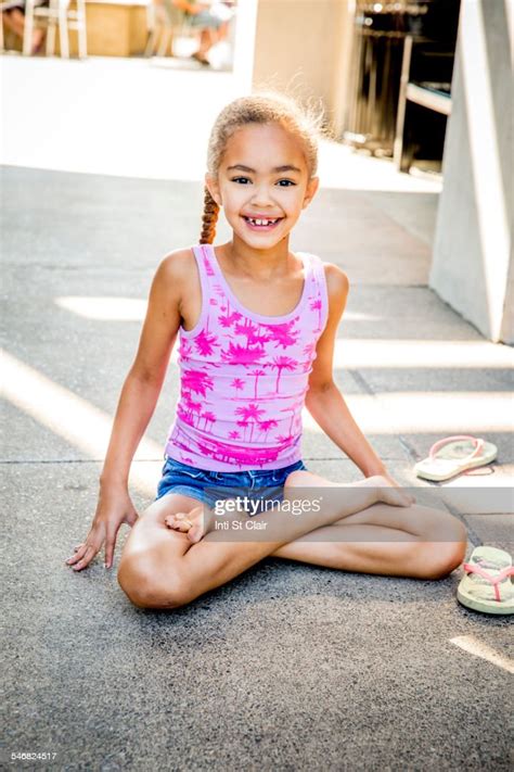 Mixed Race Girl Sitting With Legs Crossed On Sidewalk Photo Getty Images