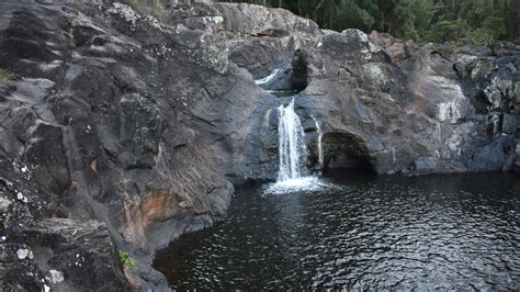 Waterfall Cascading From The Middle Of The Rocks Into A Waterhole