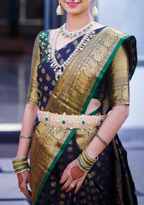 a woman in a black and gold sari with jewelry on her head smiling at the camera