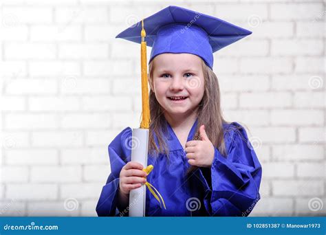 Portrait Of Cute Schoolgirl With Graduation Hat In Classroom Stock