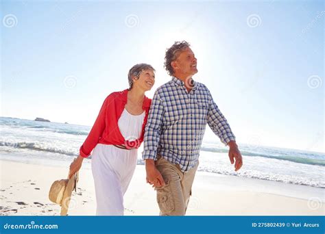 living life to its fullest a mature couple enjoying a late afternoon walk on the beach stock