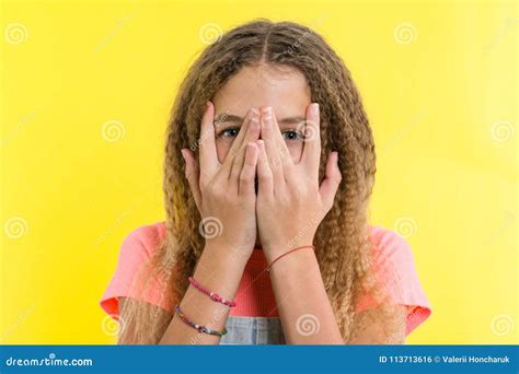 Portrait Of Teenage Girl Peeps Through Fingers Yellow Studio