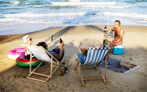 Amigos Maduros Que Comen Cervezas En La Playa Imagen De Archivo