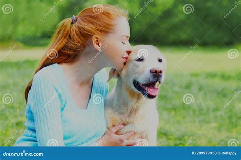 Woman Kissing Her Golden Retriever Dog On A Grass In A Park Stock Image