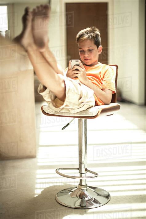 I am sitting in the morning at the diner on the corner i am waiting at the counter for the man to pour the coffee. A boy sitting looking at a mobile phone screen with feet ...