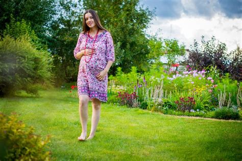Pregnant Women In A Summer Dress Walks Barefoot In The Garden Stock