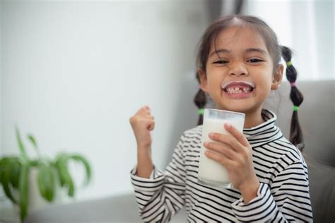 Premium Photo Asian Little Cute Kid Holding A Cup Of Milk In The