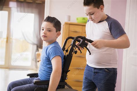 Boy Pushing Brother With Down Syndrome In Wheelchair Stock Image