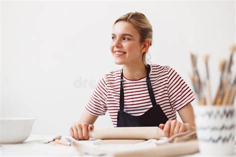 Smiling Girl In Black Apron And Striped T Shirt Sitting At The Table