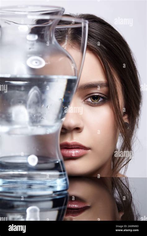 Girl Hides Her Face Behind A Glass Vase With Water Beauty Portrait Of Young Woman At The Mirror