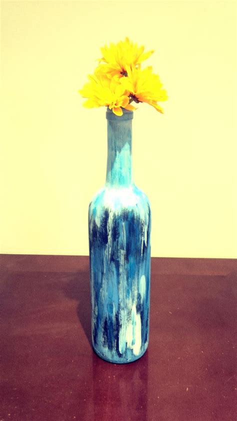 A Blue Vase With A Yellow Flower In It Sitting On A Brown Table Next To