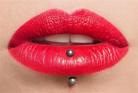 A Woman S Lips With Red Lipstick And Black Balls On The Bottom Of Her Lip