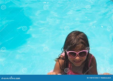 Маленькая девочка в солнечных очках улыбается в бассейне Стоковое Фото