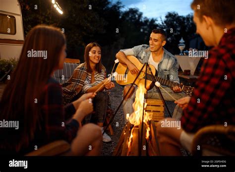 freunde die am lagerfeuer auf der gitarre spielen picknick beim camping im wald jugend mit