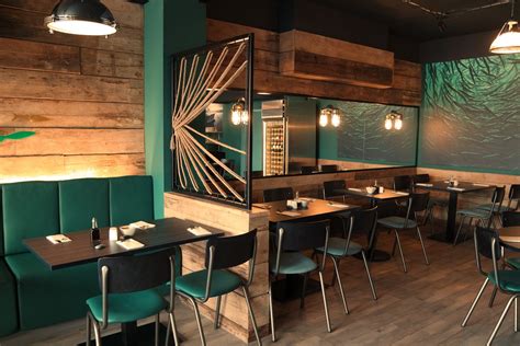the interior of a restaurant with green booths and wooden walls wood flooring and blue