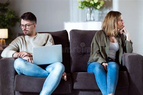 Angry Young Couple Sitting On Sofa Together And Looking To Opposite Sides At Home Stock Image