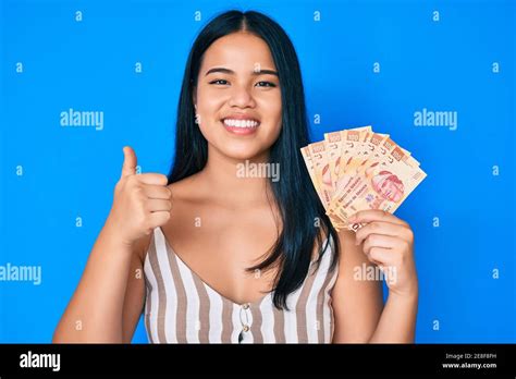 Young Beautiful Asian Girl Holding Mexican Pesos Smiling Happy And