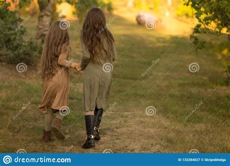 Two Girls Teenagers Go On The Green Grass Embracing Back View Stock Image Image Of Field