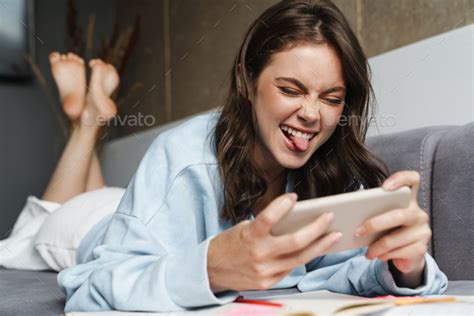 Image Of Woman Showing Her Tongue And Playing Online Game On Cellphone
