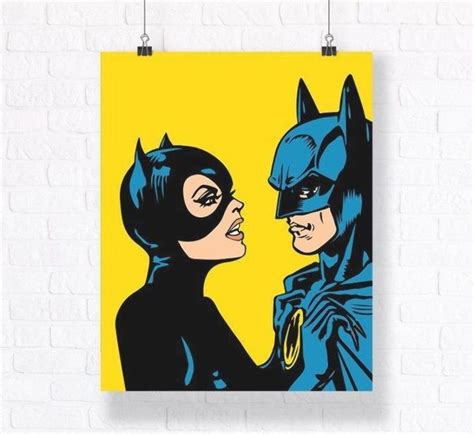 A Batman And Catwoman Poster Hanging On A Wall Next To A White Brick Wall
