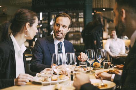 Business Coworkers Talking While Having Lunch At Restaurant Stock Photo