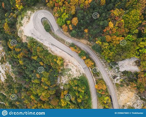 Aerial View Of A Winding Road From A High Mountain Pass Through A Dense