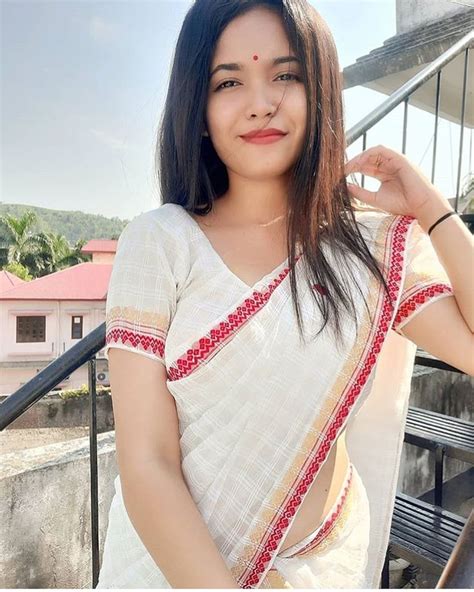 A Woman In A White Sari Posing For The Camera With Her Hands On Her Hips