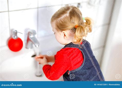 Cute Little Toddler Girl Washing Hands With Soap And Water In Bathroom