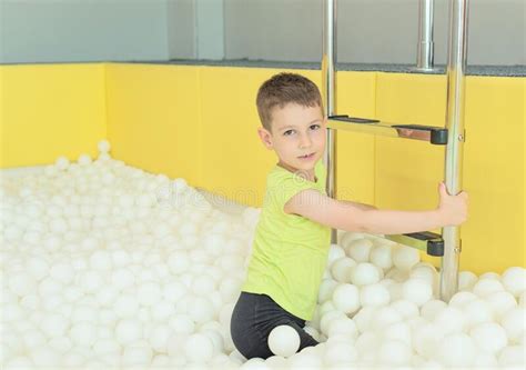Happy Child Boy In The Big Dry Pool With Thousand Of White Balls