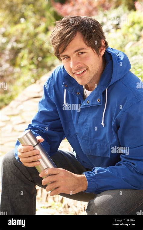 Young Man Relaxing With Thermos Flask In Autumn Landscape Stock Photo
