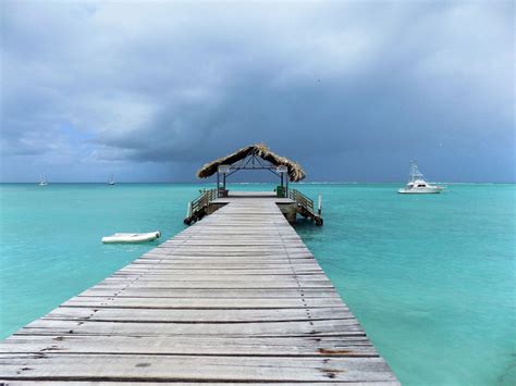 this photo shows a wooden jetty with a thatched shelter at the end of it tobago travel soca