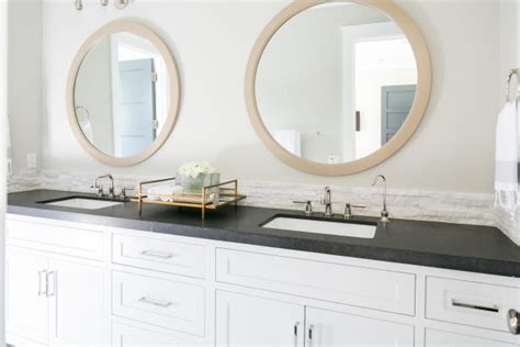 A common approach is to make the mirror exactly as wide as the vanity so the two line up. Transitional Double Vanity Bathroom With Round Mirrors | HGTV