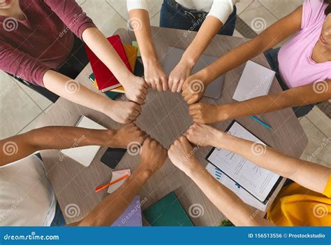 Multiracial Students Joining Hands Together In Cooperation Stock Photo