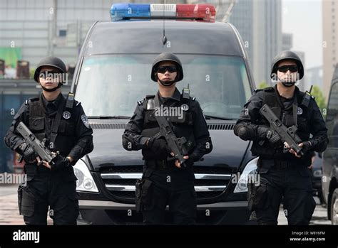 Swat Police Officers Armed With Guns Stand Guard Next To A Police Cruiser At The Square Of The