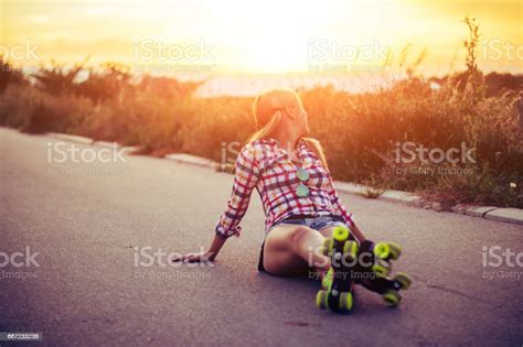 Young Woman With Roller Skates Sitting And Relaxing In The Street In