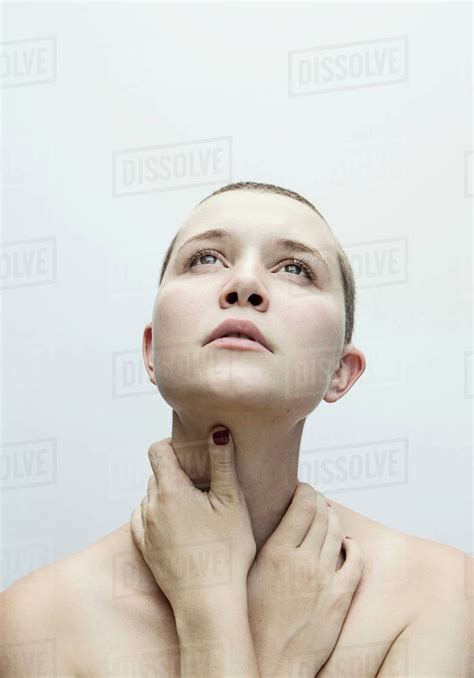 Woman With Shaved Head Holding Neck With Hands Stock Photo Dissolve