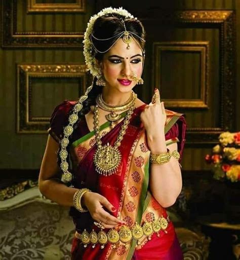a woman in a red and green sari with gold jewelry on her head is posing for the camera
