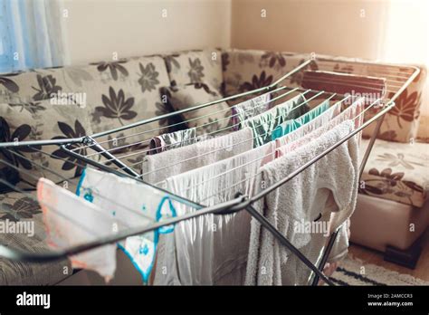 clean clothes hanging on dryer after washing at home housekeeping and household chores stock