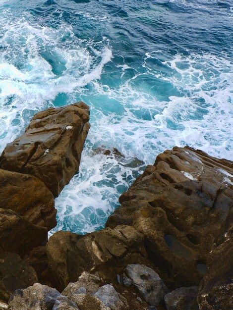 Premium Photo Vertical Aerial View Of Sea Waves Hitting The Stone