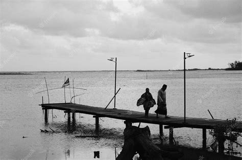 Premium Photo Two Men Walk On A Dock In Front Of A Cloudy Sky