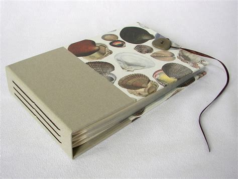 An Open Book With Various Seashells On The Cover And Cord Attached To It