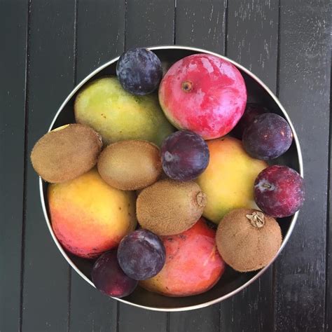 A Metal Bowl Filled With Fruit On Top Of A Wooden Table